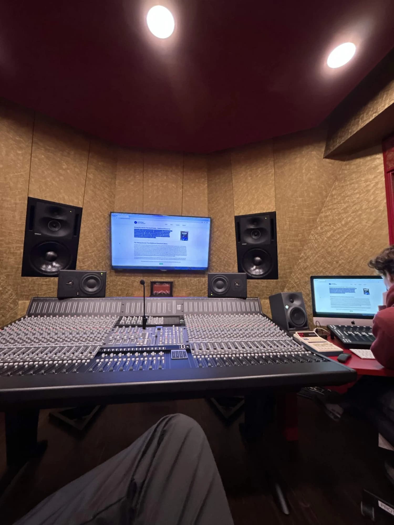 Large-format mixing console with Genelec monitors in a studio control room